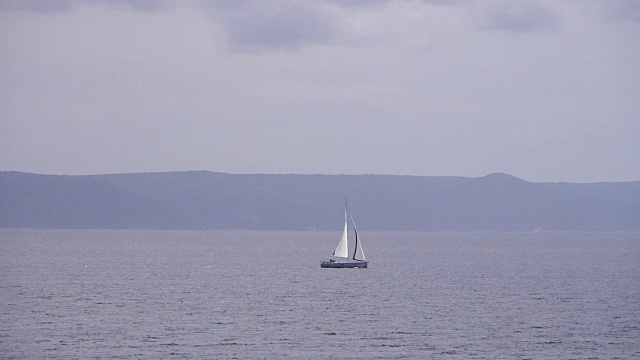 帆船在多云的天气中航行，背景是美丽的海景。不认识的人的剪影。视频素材