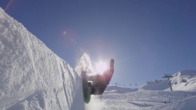 慢动作:年轻的专业滑雪板运动员在阳光灿烂的雪园的半管喷洒雪视频下载