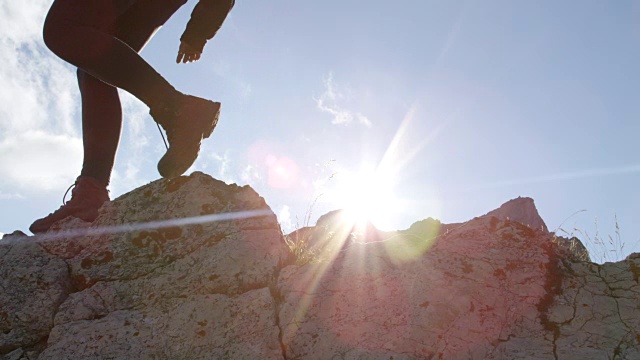 低角度:难以辨认的女徒步者穿着皮靴爬上山顶视频素材