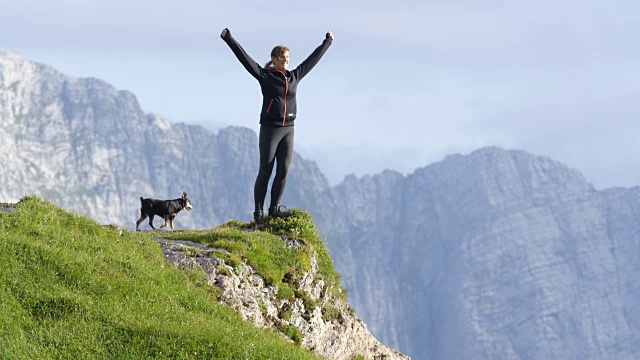 慢镜头:一个女人站在山的边缘，双手高高举起视频素材