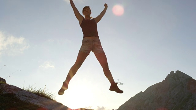 近:微笑的女性在山上跳高，伸出手，腿视频素材