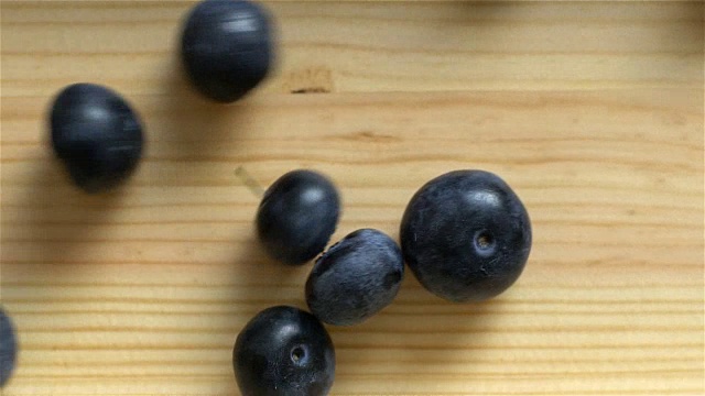 许多蓝莓在木头表面滚动。缓慢的运动。前视图。视频素材