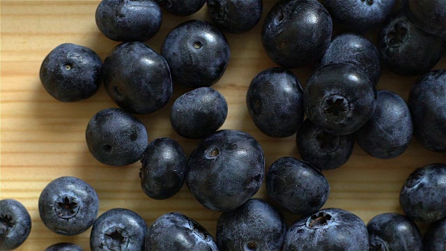 许多蓝莓在木头表面滚动。缓慢的运动。前视图。视频素材