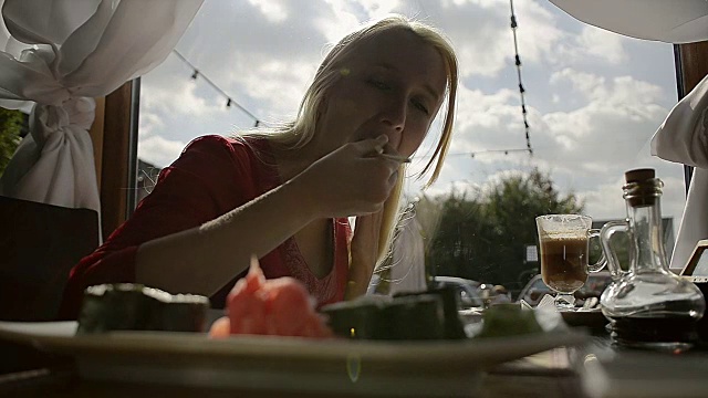 在餐馆里用筷子蘸酱油吃寿司的女孩视频素材