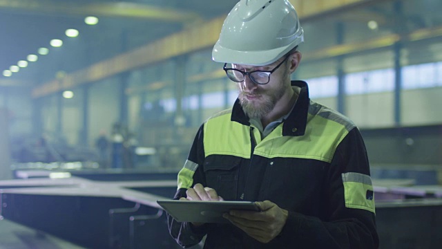 安全帽工程师正在一家重工业工厂里使用平板电脑。视频素材