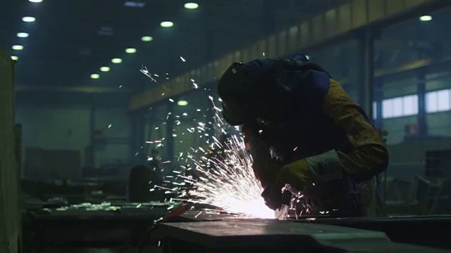 在一个工厂的重工业工人正在一个角磨床上与金属工作，而热火花产生的结果。视频素材