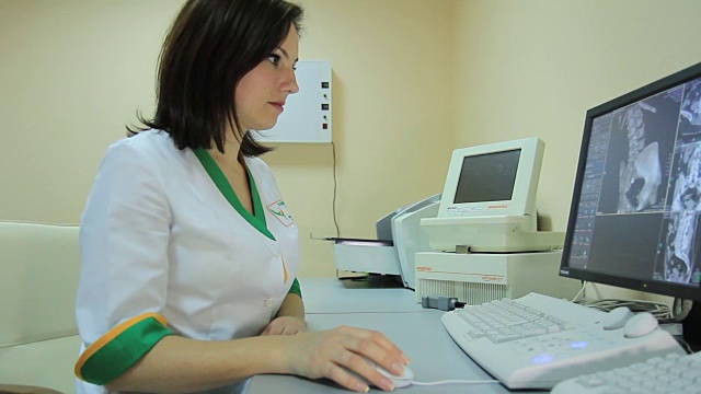 一位女医生启动核磁共振扫描仪，在监视器上查看结果视频下载