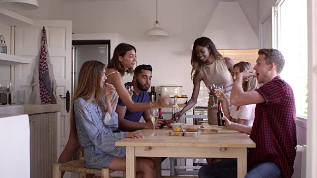 年轻的成年人朋友在厨房里喝着、吃着零食，拍摄于R3D视频素材