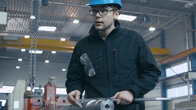 工厂工人正在用测量工具对一个金属零件进行质量控制。视频素材