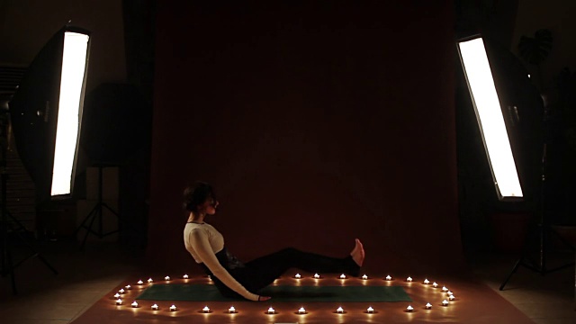 年轻女子在黑暗中做盘子或瑜伽练习视频下载