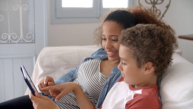 母亲和孩子在沙发上使用数字平板电脑视频素材