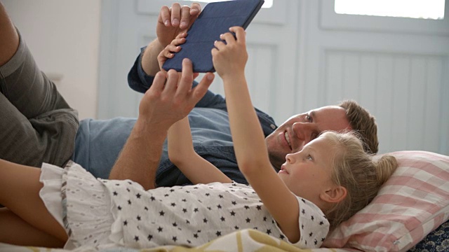 父亲和女儿躺在地板上使用数码平板电脑视频素材