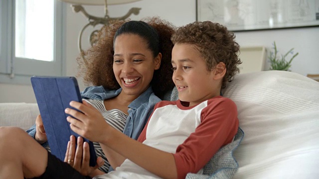 母亲和儿子在沙发上使用数码平板电脑视频素材