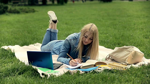 女学生在校草坪上学习。视频素材