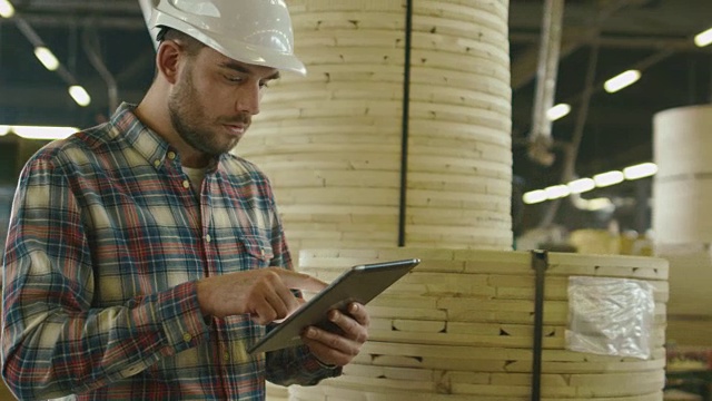 工人正在木材工厂的仓库里使用平板电脑。视频素材