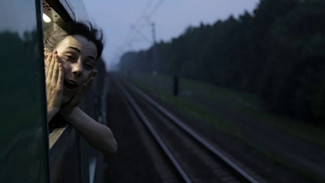 晚上的肖像快乐的女女孩微笑和尖叫扔在火车打开的火车窗口视频下载