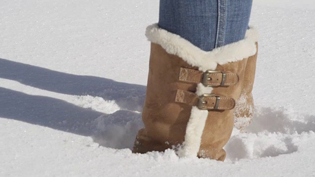 近距离观察:一个不知名的女人穿着冬靴在新鲜的雪地里跳来跳去视频下载