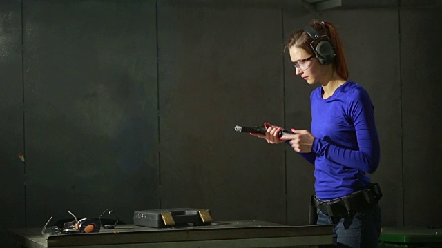 一个持枪的年轻女子在室内射击场。收集枪视频下载