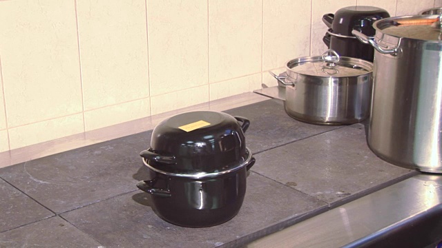 在餐厅厨房的工作炉上用统一的有盖平底锅做饭。烹饪。毛巾视频下载