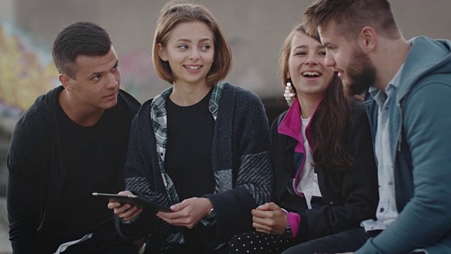 一群在城市环境中使用平板电脑进行户外娱乐的微笑和大笑的青少年。视频素材