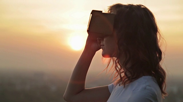 一名女子在日落时佩戴虚拟现实眼镜视频下载