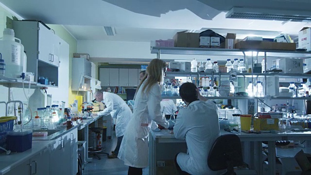 一群穿着白大褂的白种科学家正在一个现代化的实验室里工作。视频素材