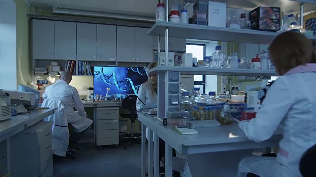 一群穿着白大褂的白种科学家正在一个现代化的实验室里工作。视频素材