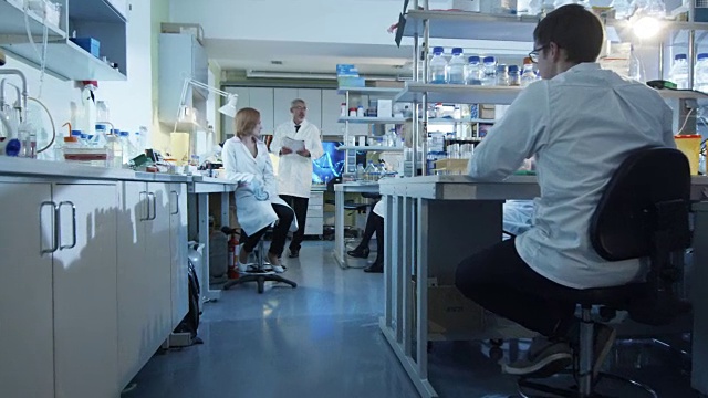 身穿白大褂的实验室科学家正在工作场所庆祝。视频素材