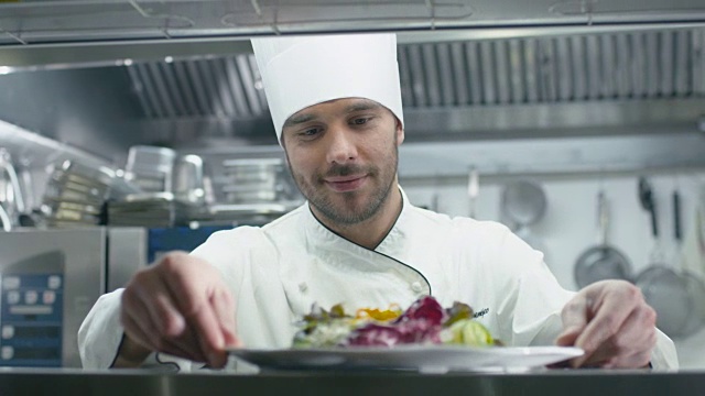 在一家餐馆或酒店的商业厨房里，快乐的专业厨师正在提供沙拉。视频素材