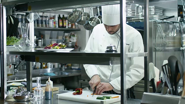 商业厨房里的专业厨师正在切绿色蔬菜。视频素材