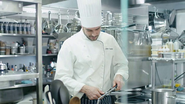 饭店或酒店的商业厨房里的专业厨师正在磨刀。视频素材