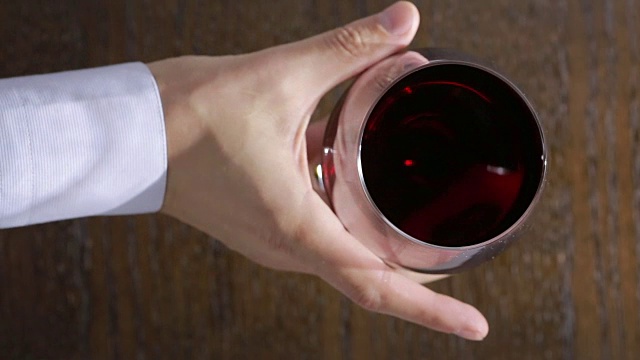 侍酒师的手拿着一杯红酒。视频下载