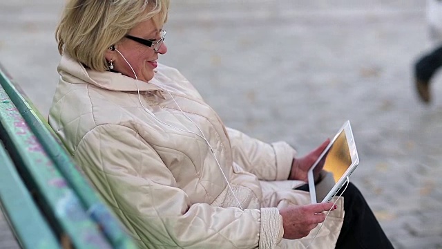 女人坐在长椅上，通过平板电脑交流视频素材