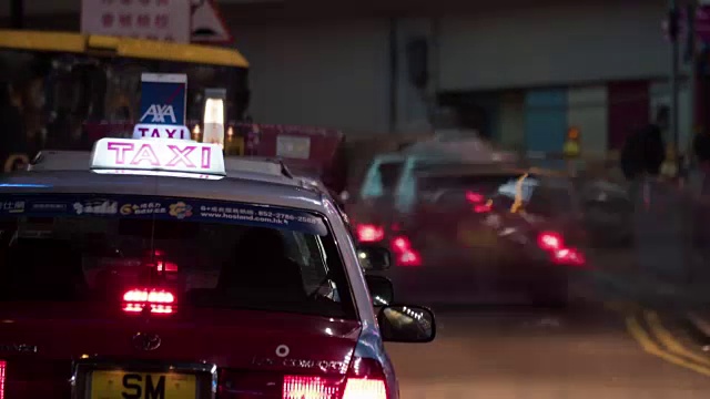近夜景出租车排队等待乘客，模糊的人在交通背景。中国香港视频下载