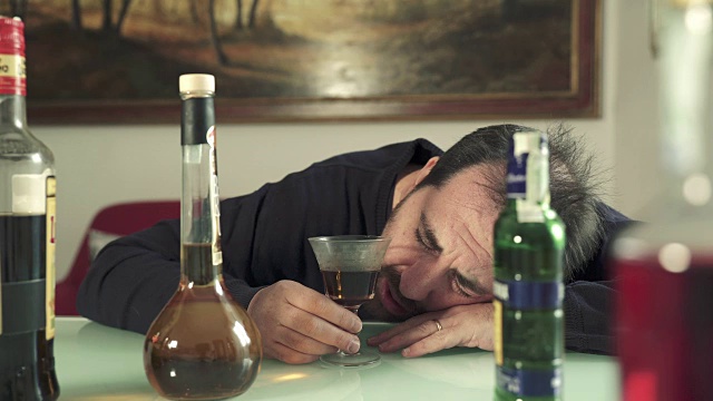 一个绝望的醉汉靠在桌子上喝了一杯酒视频素材