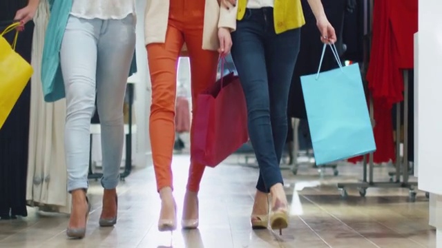 低镜头的女性腿走过一个百货公司在彩色服装。视频购买