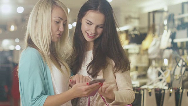 两个快乐的年轻女孩在一家百货商店里使用智能手机。视频素材
