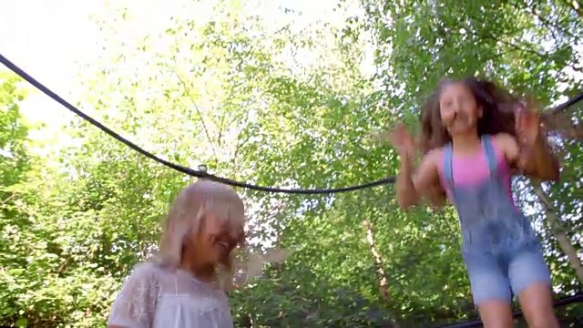 两个女孩在蹦床上跳的慢动作射击视频素材