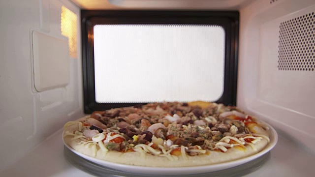 微波炉里解冻冷冻海鲜披萨的人把晚餐放进烤箱视频下载