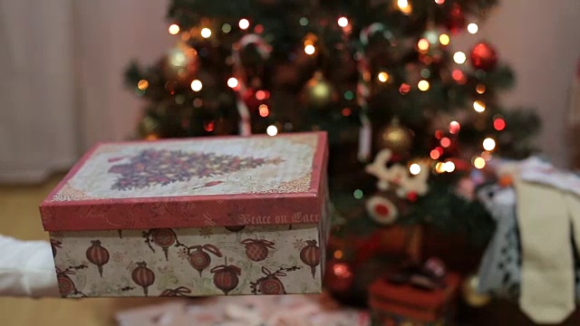 在闪闪发光的圣诞树前接受礼物的手视频素材