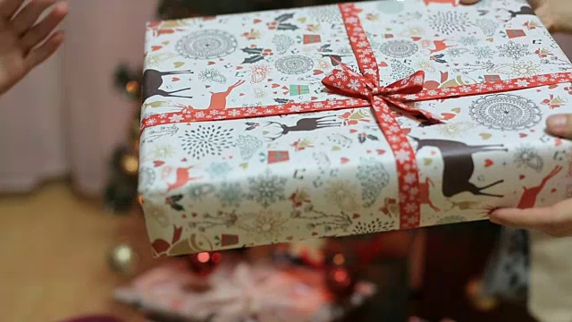在闪闪发光的圣诞树前接受礼物的手视频素材