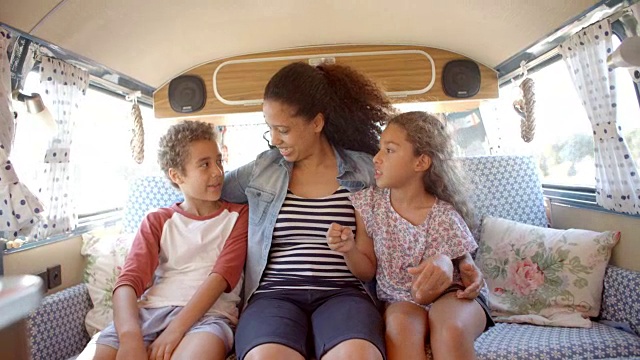 微笑的妈妈和孩子们坐在露营车的后面视频素材