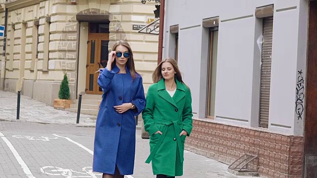 两个女人穿着羊绒大衣走在大街上。慢慢地视频下载