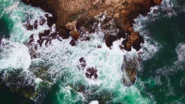 鸟瞰图的岩石海岸线和撞击的海浪在悬崖上视频素材