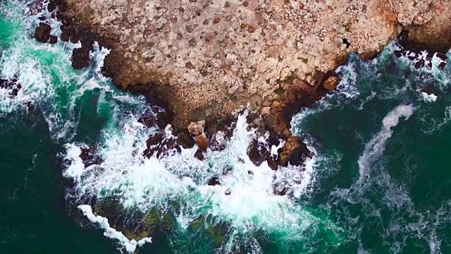 鸟瞰图的岩石海岸线和撞击悬崖的海浪视频素材
