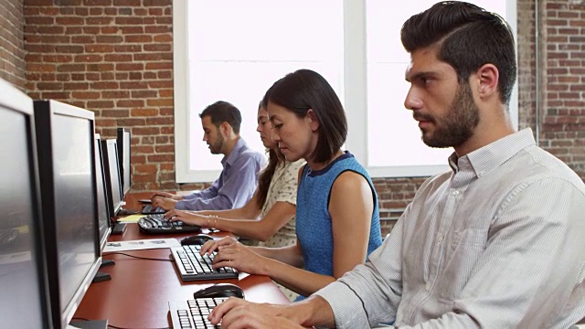 工作人员坐在办公桌前使用电脑在R3D拍摄视频素材