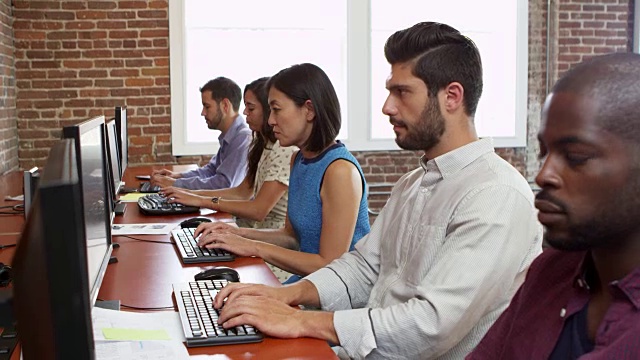 工作人员坐在办公桌前使用电脑在R3D拍摄视频素材