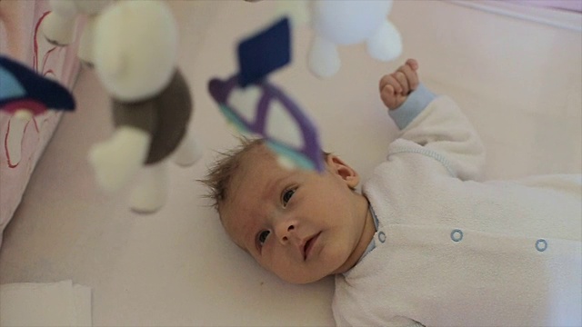 婴儿在婴儿床里照看着她的玩具视频下载
