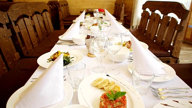 庆祝餐桌上，餐盘摆在桌上，刀叉、刀叉、刀叉摆在盘子旁边，肉、鱼、沙拉摆在洁白美丽的餐桌上视频下载