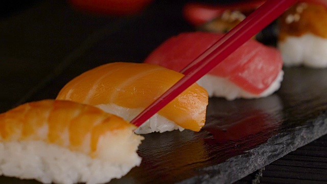 近距离的红色筷子取寿司卷的桌子上的餐厅视频素材